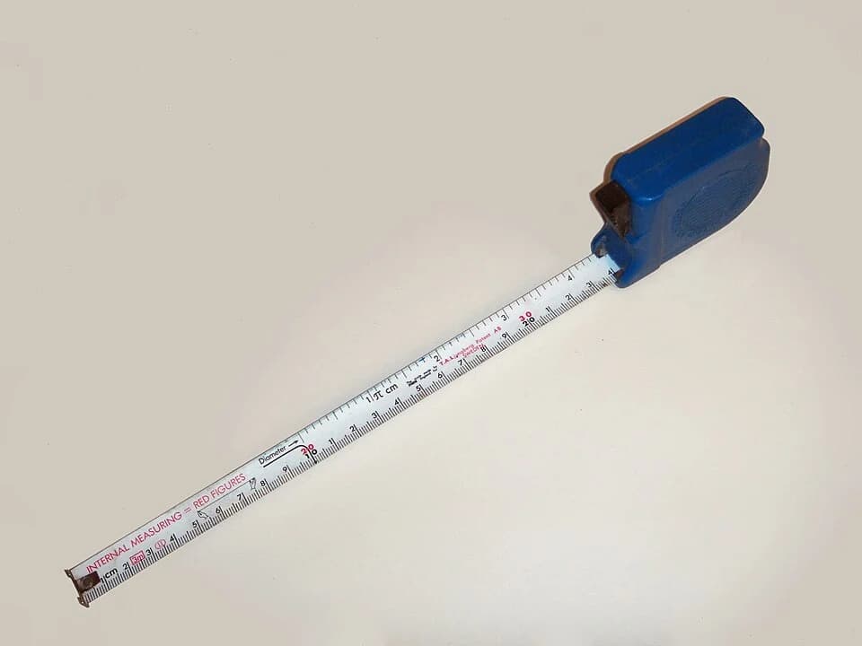 An extended measuring tape showing metric and inch scales.