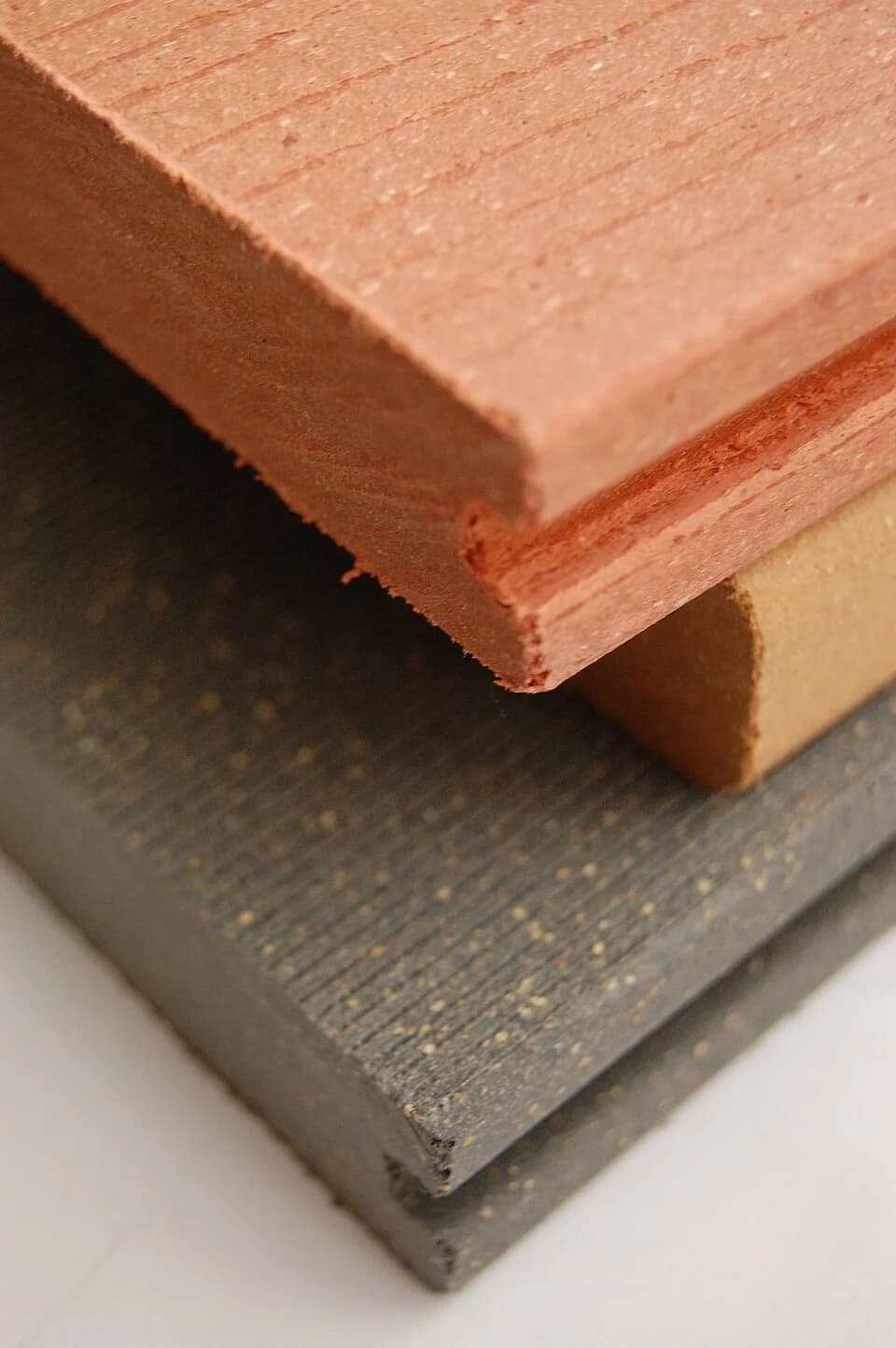 Stacked wood-plastic composite samples showing different colors, cut edges and surface textures.
